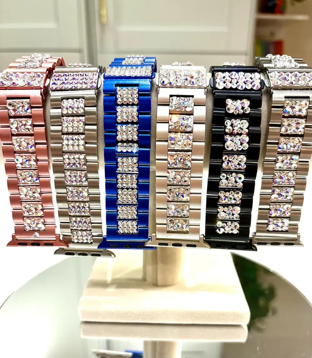 Swarovski Crystal Smart Watch Bracelet in various colors, featuring sparkling crystals on a stainless steel strap, displayed on a stand.