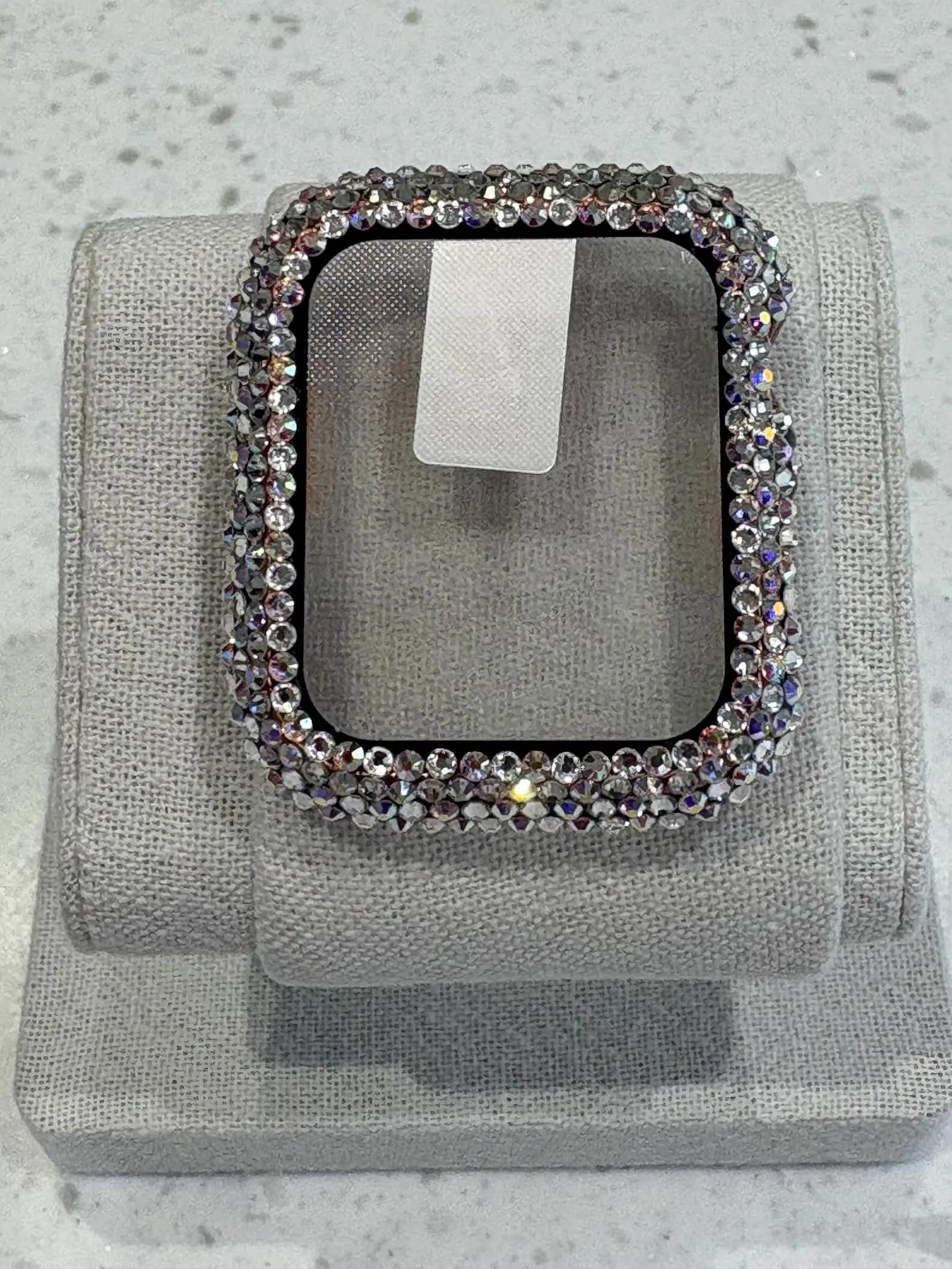 Luxury Watch Screen Case with Preciosa® Crystals, displayed on a gray fabric stand, showcasing sparkling crystal embellishments.