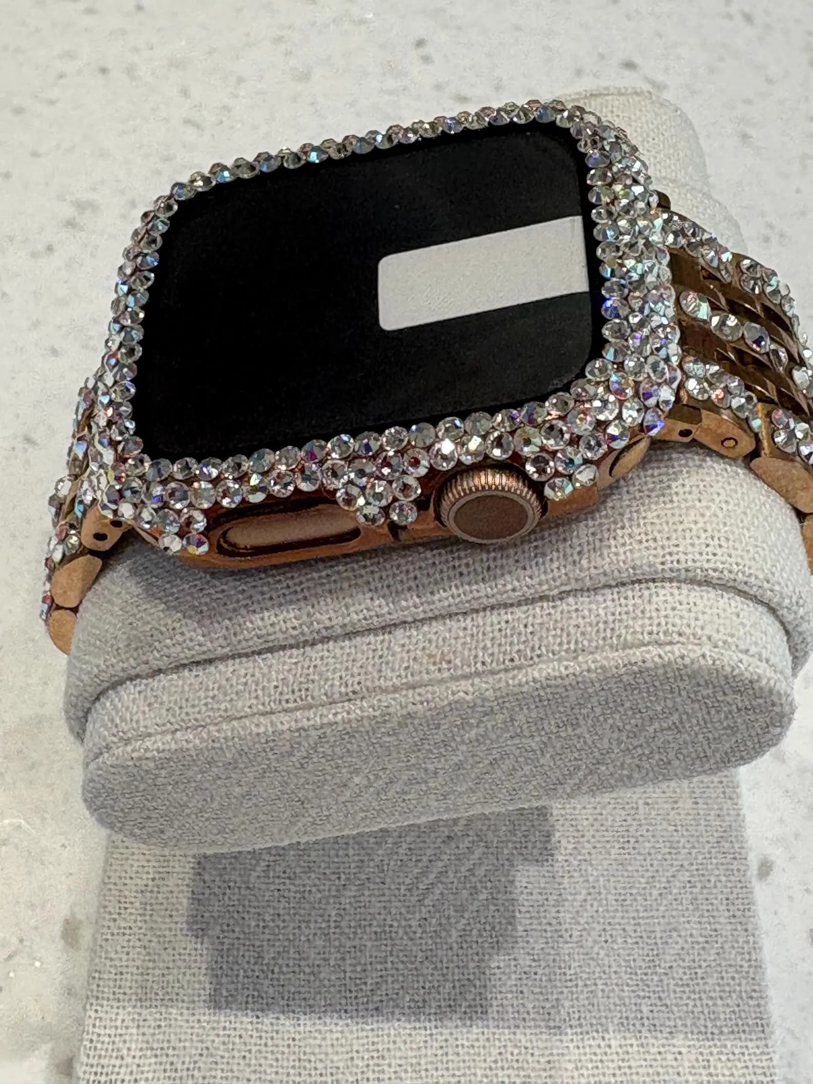 Luxury Watch Screen Case with Preciosa® Crystals, surrounded by sparkling crystals, displayed at an angle on a cushioned stand.