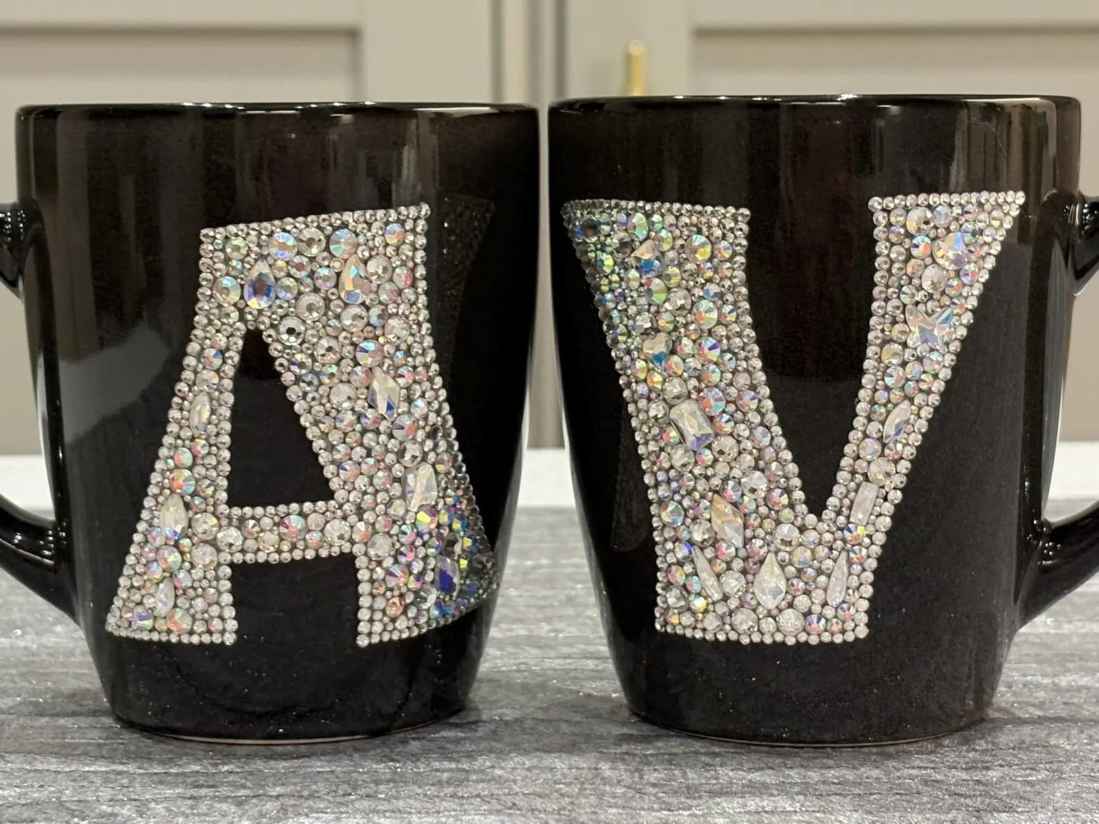 Personalized Crystal Initial Mug with letters "A" and "V" in sparkling crystals on black ceramic, shown from the front.