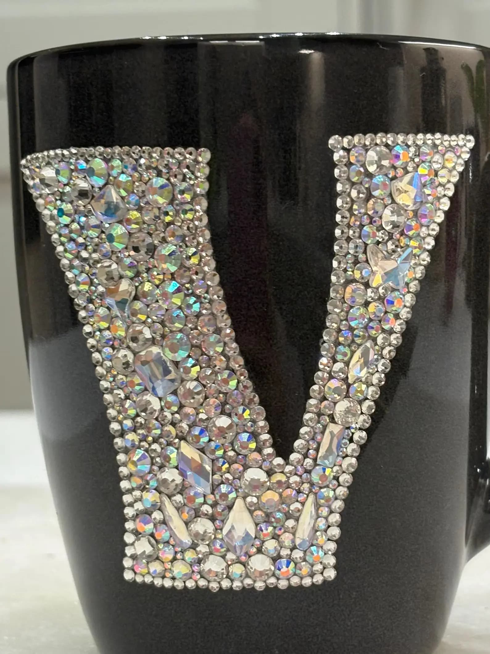 Personalized Crystal Initial Mug featuring a large "V" adorned with sparkling crystals on a black ceramic surface.