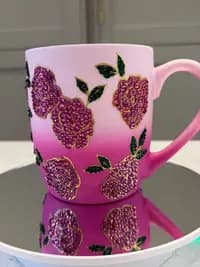 Sparkling Crystal Flower Mug with pink gradient and embellished floral design, displayed on a mirrored surface showing its reflection.