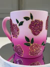 Sparkling Crystal Flower Mug with pink gradient and rhinestone floral design, shown close-up on a mirrored surface.
