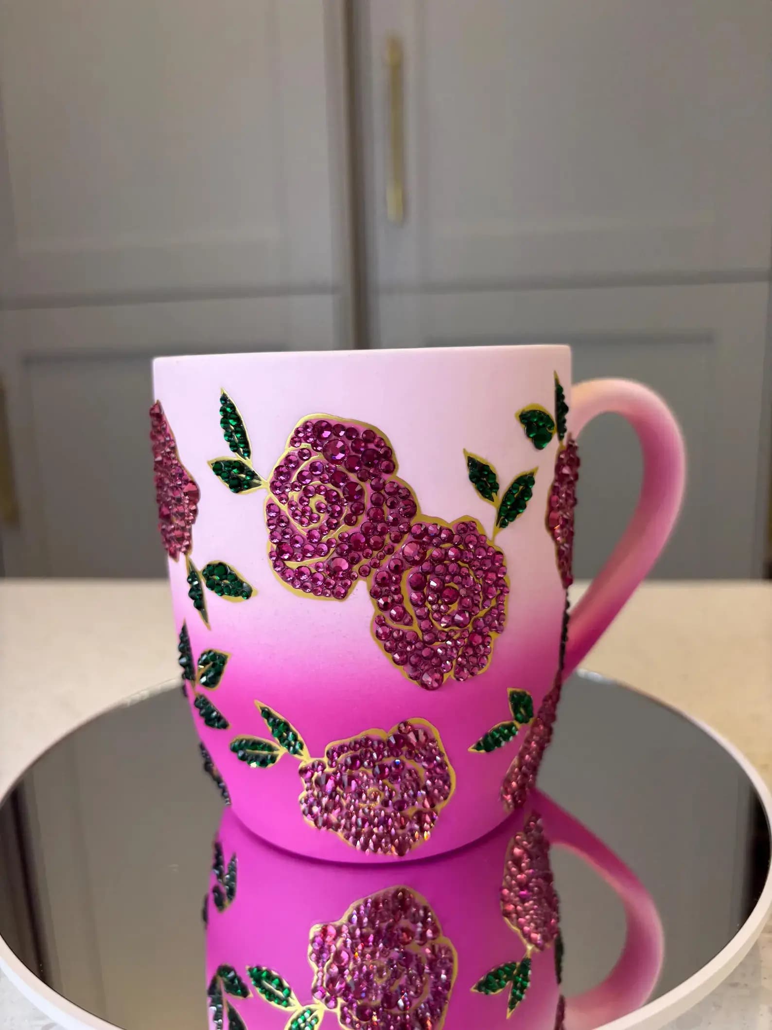 Sparkling Crystal Flower Mug with pink gradient design, decorated with glittering pink and green floral crystals on a mirrored surface.